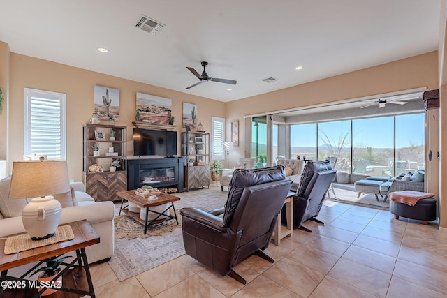 living area featuring light tile patterned flooring, visible vents, recessed lighting, and a glass covered fireplace