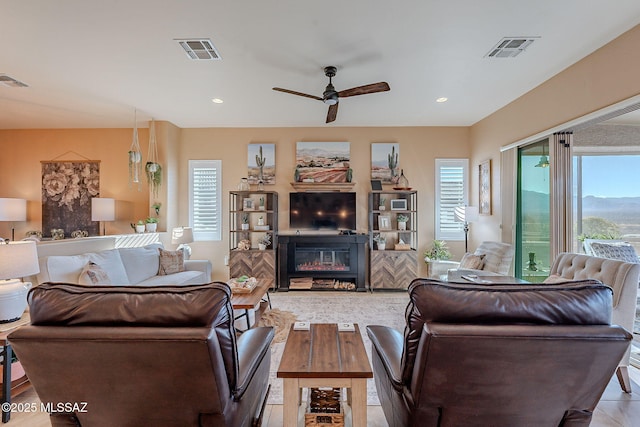 living room with visible vents, plenty of natural light, and a glass covered fireplace