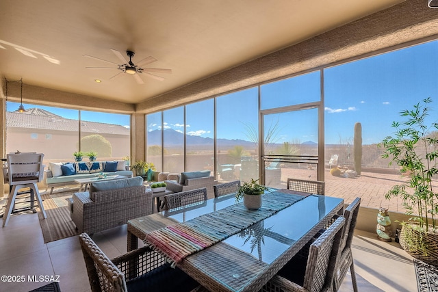 sunroom with a mountain view, plenty of natural light, and a ceiling fan