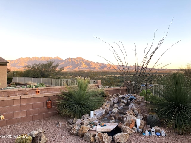 yard at dusk with a mountain view and fence