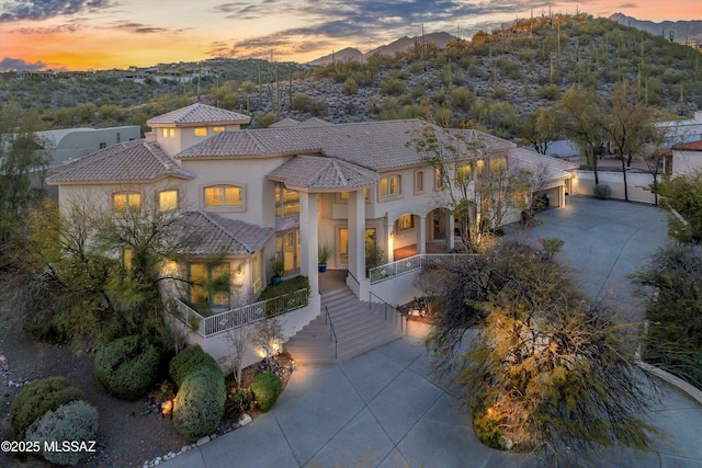 mediterranean / spanish home featuring concrete driveway, a tile roof, a mountain view, and stucco siding