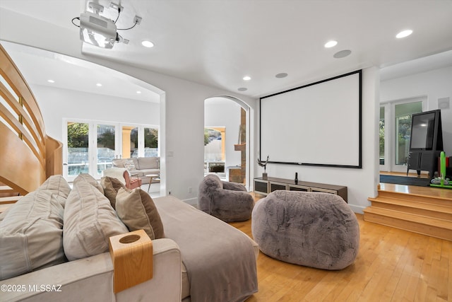 home theater room featuring light wood-style floors, baseboards, arched walkways, and recessed lighting