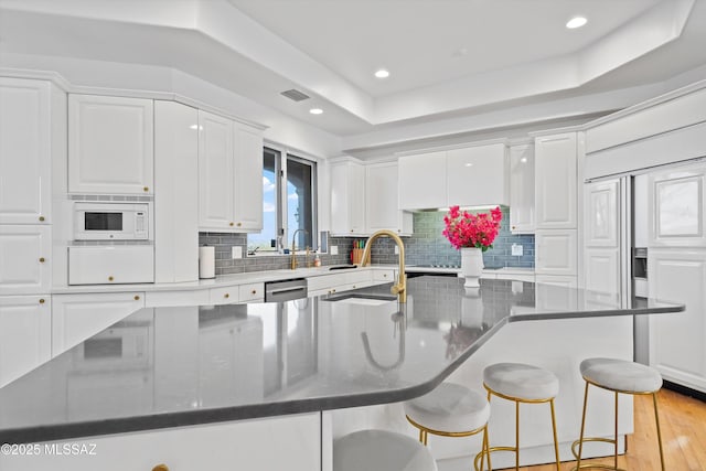 kitchen featuring white microwave, a sink, visible vents, and white cabinets