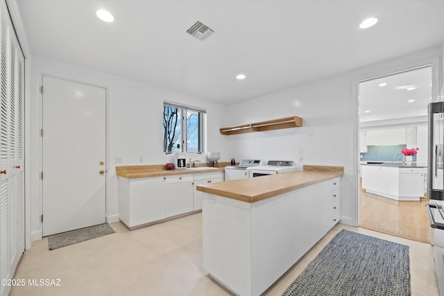 kitchen with washing machine and clothes dryer, open shelves, recessed lighting, white cabinets, and a peninsula