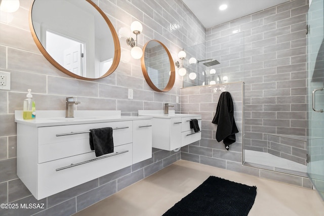 bathroom featuring tile walls, two vanities, decorative backsplash, a sink, and a tile shower