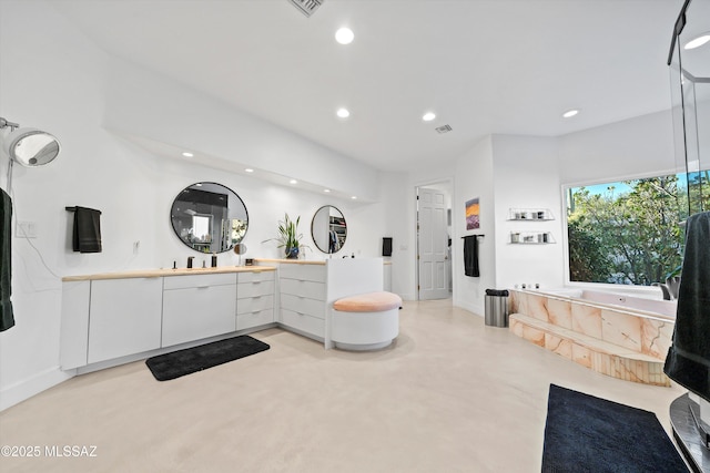 bathroom featuring finished concrete flooring, vanity, a bath, and recessed lighting