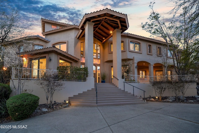 mediterranean / spanish-style house featuring a tile roof, stairway, and stucco siding