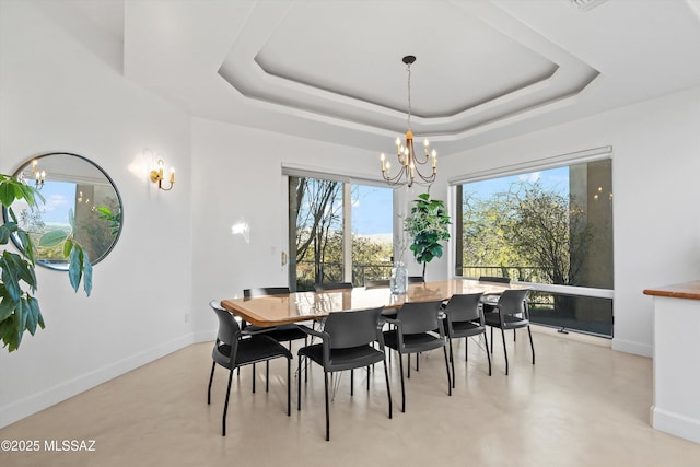 dining room with finished concrete floors, a tray ceiling, baseboards, and an inviting chandelier