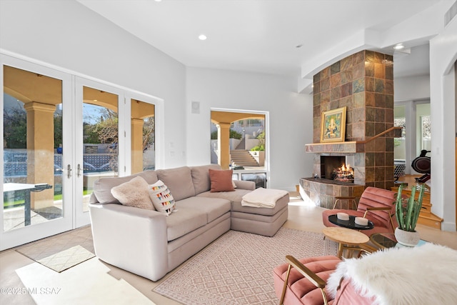 living room featuring a tile fireplace, french doors, plenty of natural light, and light tile patterned floors