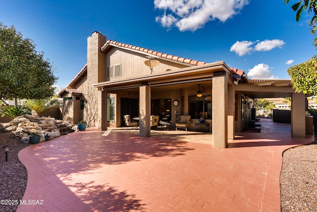 rear view of house featuring fence, stucco siding, a chimney, a patio area, and a ceiling fan