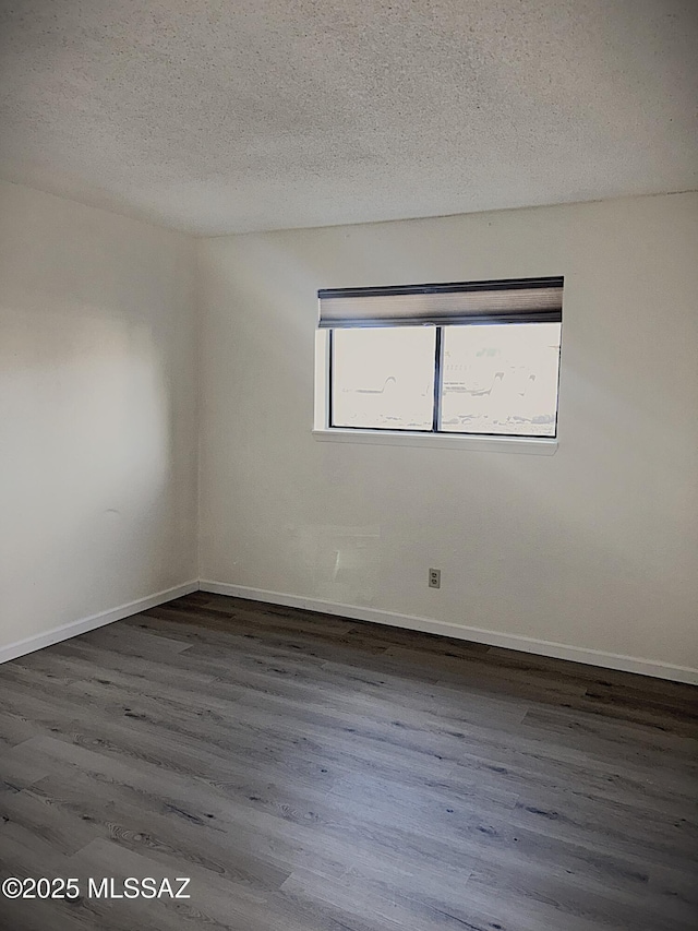 empty room with a textured ceiling, baseboards, and wood finished floors