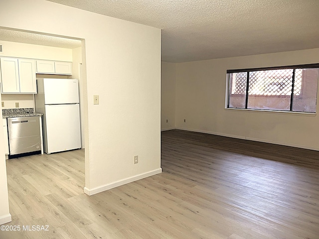 unfurnished room featuring light wood finished floors, baseboards, and a textured ceiling