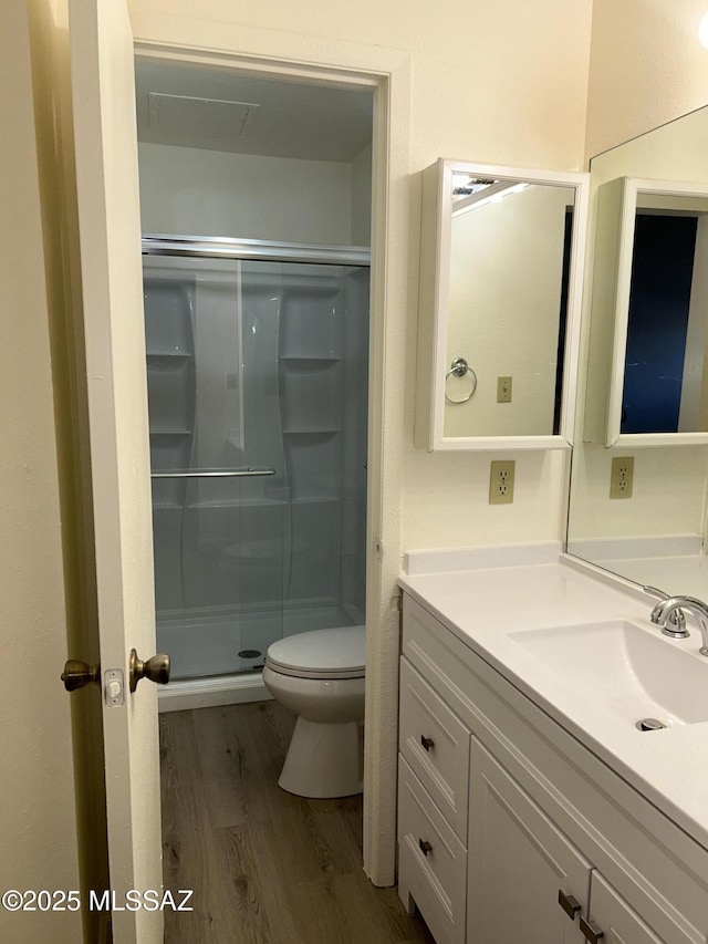 full bath featuring vanity, a stall shower, wood finished floors, and toilet