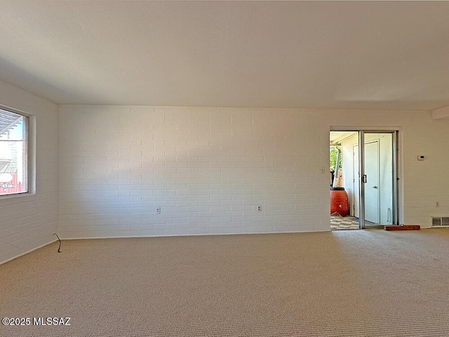 spare room featuring carpet floors and brick wall