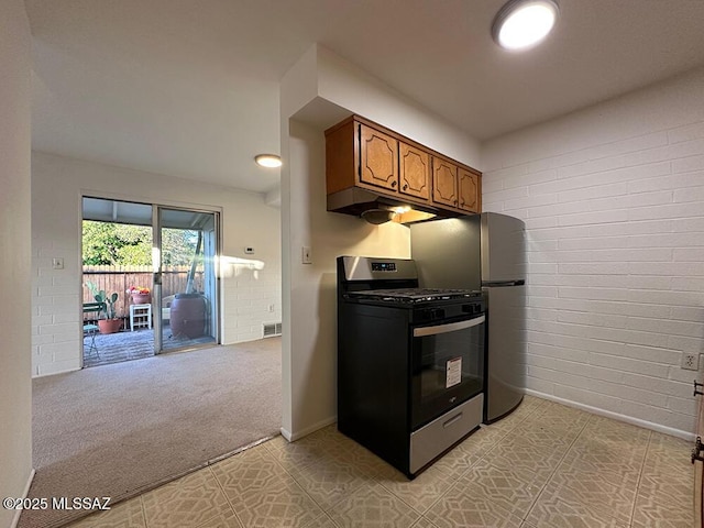 kitchen with brick wall, brown cabinetry, stainless steel appliances, baseboards, and visible vents