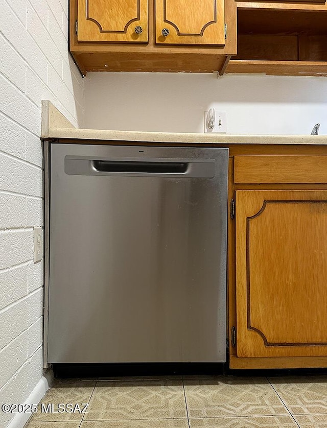 interior details featuring stainless steel dishwasher, brown cabinets, and light countertops