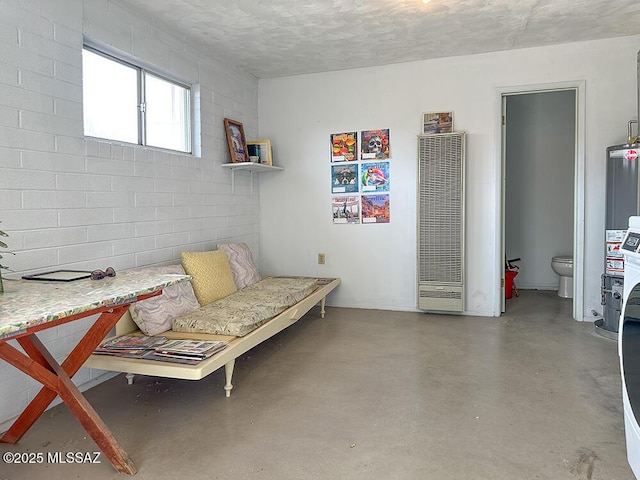 living area with finished concrete floors, a heating unit, a textured ceiling, and gas water heater