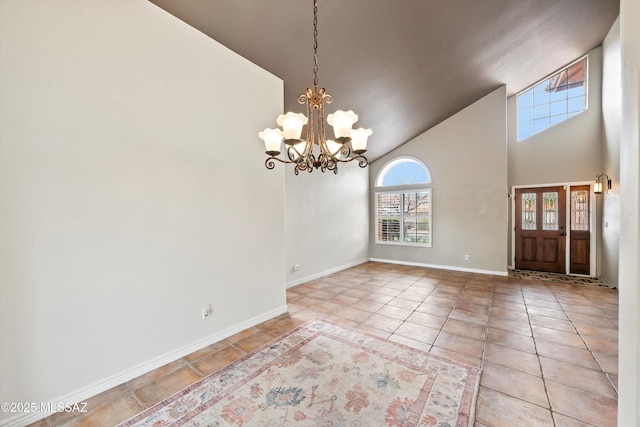 tiled entrance foyer with baseboards, a towering ceiling, and a chandelier