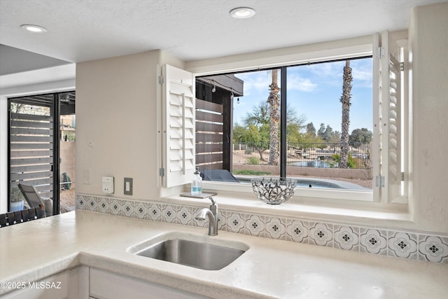 kitchen with a sink, white cabinetry, recessed lighting, and light countertops