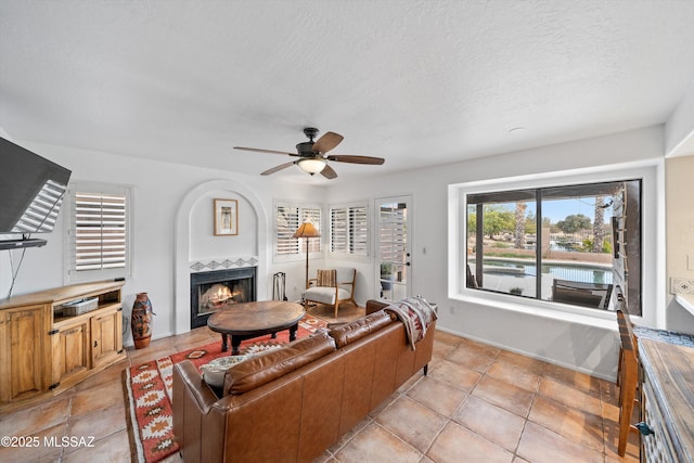 living area featuring a textured ceiling, a ceiling fan, and a tile fireplace