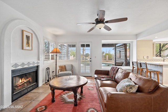 living room featuring a ceiling fan, a healthy amount of sunlight, light tile patterned flooring, and a fireplace