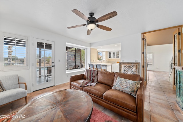 living room featuring light tile patterned floors, a ceiling fan, and baseboards