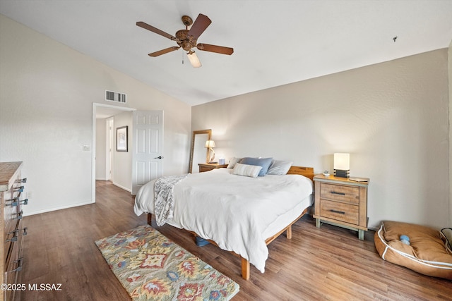 bedroom featuring visible vents, baseboards, wood finished floors, and vaulted ceiling