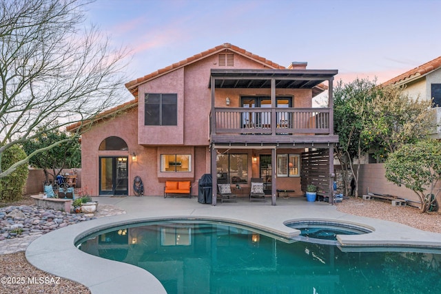 back of property at dusk featuring stucco siding, a patio, stairs, and fence