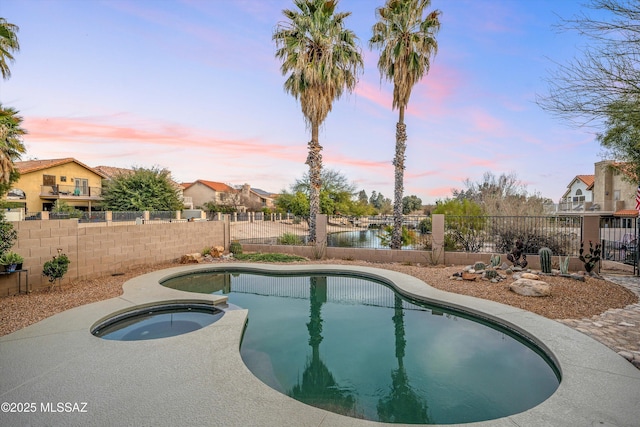 view of swimming pool featuring a pool with connected hot tub and a fenced backyard