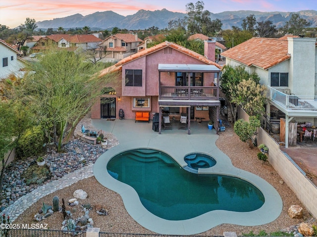 pool at dusk with a mountain view, a fenced in pool, a fenced backyard, and a patio area