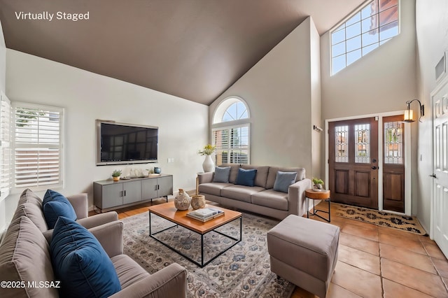 living area with visible vents, light tile patterned flooring, and vaulted ceiling