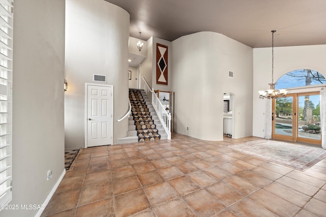 unfurnished living room with visible vents, stairway, a high ceiling, and an inviting chandelier