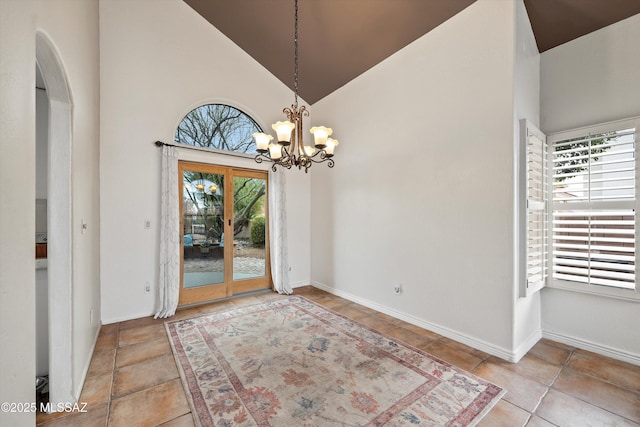 unfurnished dining area featuring a chandelier, arched walkways, high vaulted ceiling, and baseboards