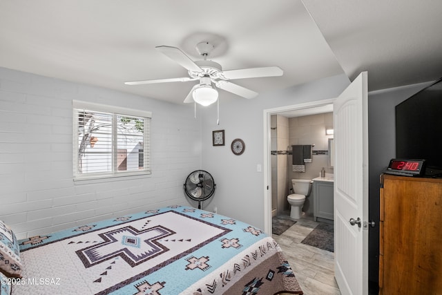 bedroom featuring light wood-type flooring, connected bathroom, brick wall, and ceiling fan