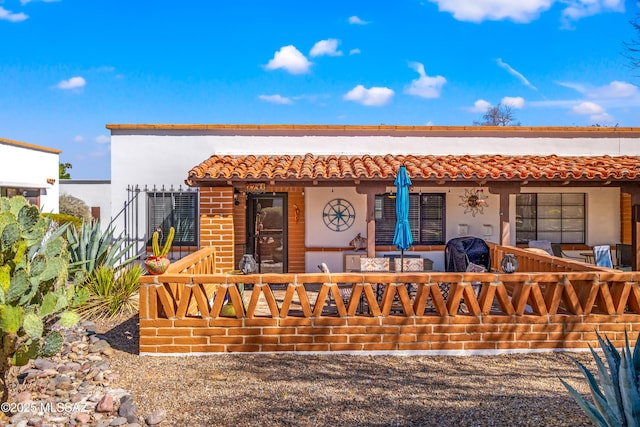 exterior space with covered porch, a tiled roof, and stucco siding