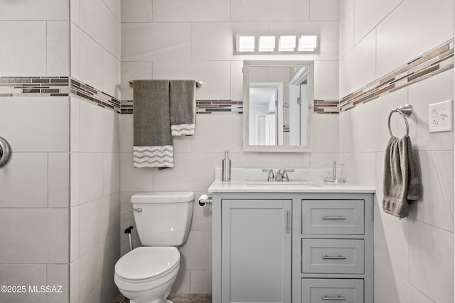 bathroom featuring toilet, tile walls, and vanity