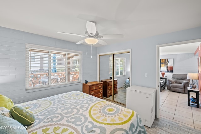 bedroom with a closet, ceiling fan, light wood-style flooring, and fridge