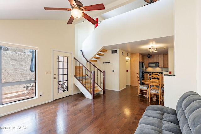 living room with dark wood-style floors, visible vents, high vaulted ceiling, and stairs