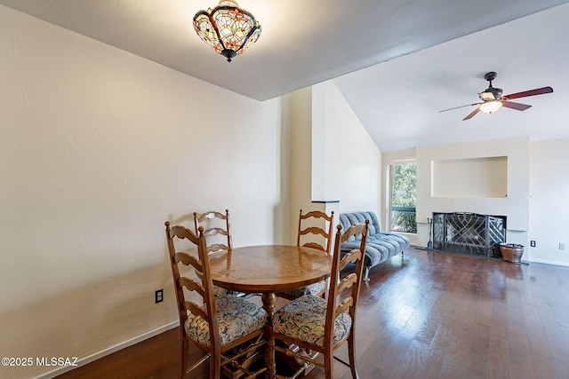 dining room with hardwood / wood-style floors, baseboards, lofted ceiling, a fireplace, and ceiling fan