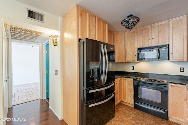 kitchen with black appliances, dark countertops, visible vents, and light brown cabinetry