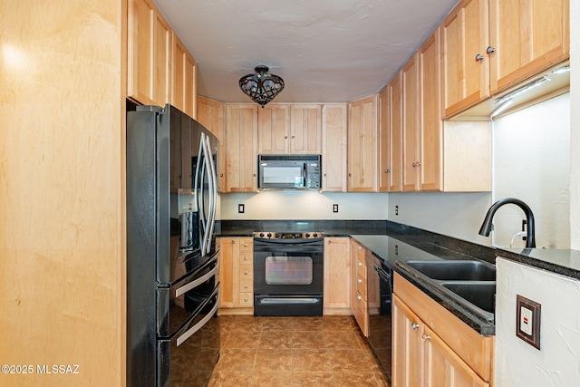 kitchen with a sink, dark countertops, black appliances, and light brown cabinets