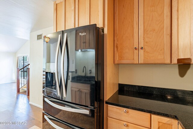 kitchen featuring dark countertops, visible vents, light brown cabinets, vaulted ceiling, and black refrigerator with ice dispenser