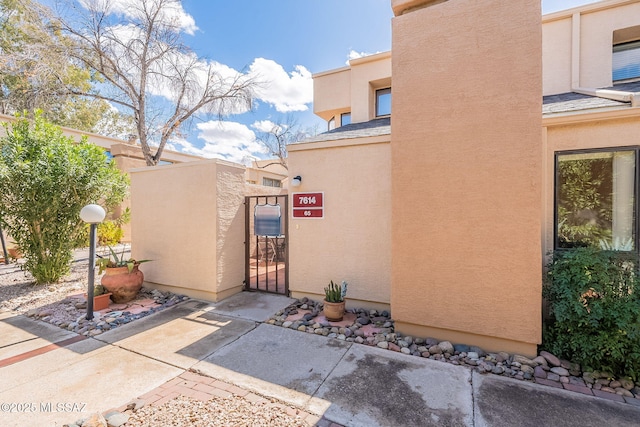 exterior space with a gate and stucco siding