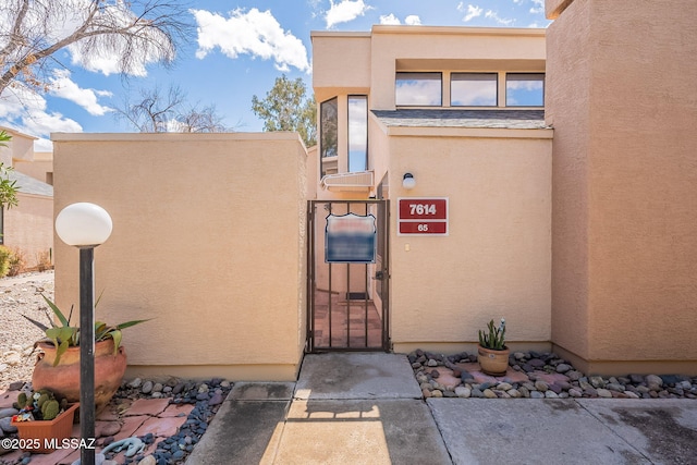 doorway to property featuring stucco siding and a gate