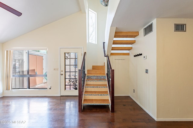 staircase featuring vaulted ceiling, visible vents, baseboards, and wood finished floors