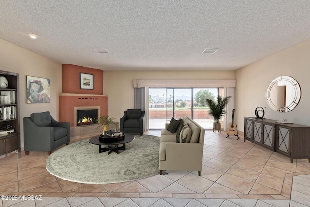 living room with light tile patterned floors, visible vents, a warm lit fireplace, and a textured ceiling