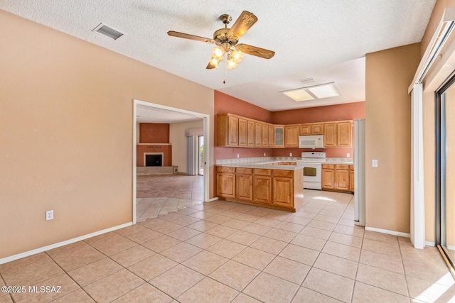 kitchen featuring white appliances, a fireplace with raised hearth, light tile patterned flooring, and light countertops