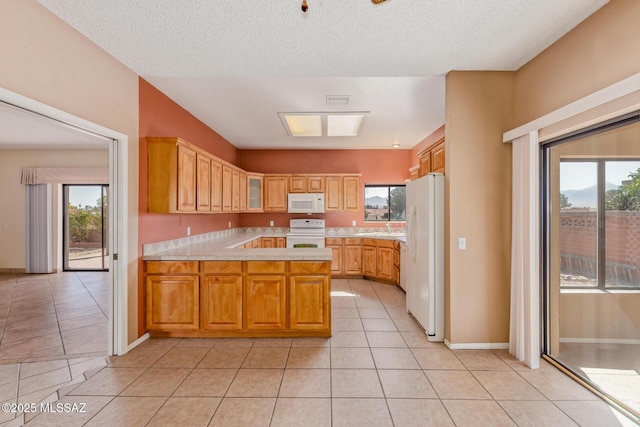 kitchen featuring a sink, white appliances, a peninsula, light tile patterned flooring, and light countertops