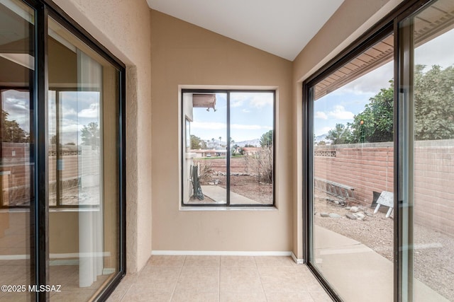 doorway with light tile patterned flooring, plenty of natural light, baseboards, and lofted ceiling