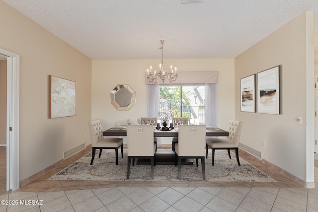 dining space with tile patterned flooring, a textured ceiling, and an inviting chandelier